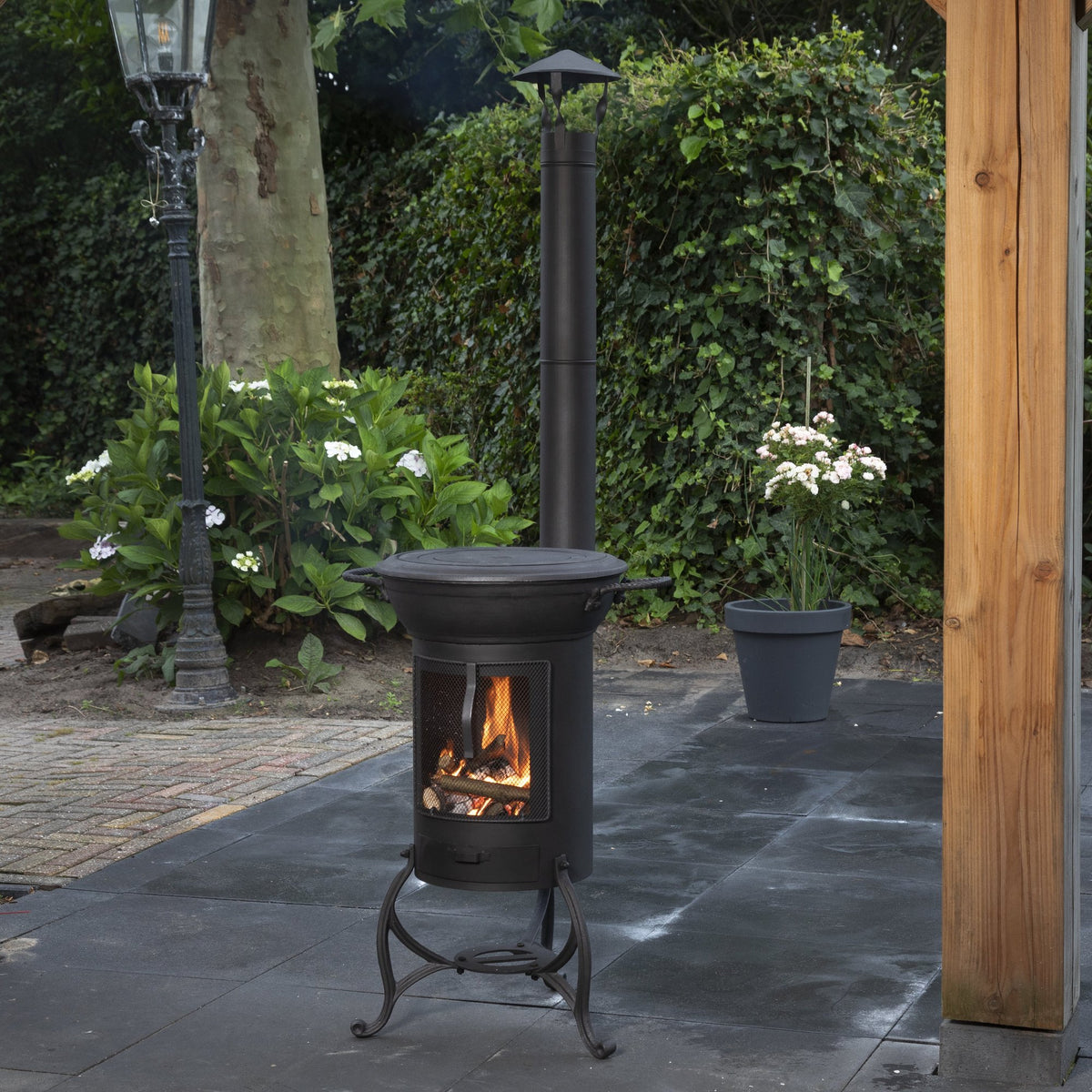 Poêle d'extérieur Globe-fire Krakatau - corps cylindrique avec flamme dans un jardin